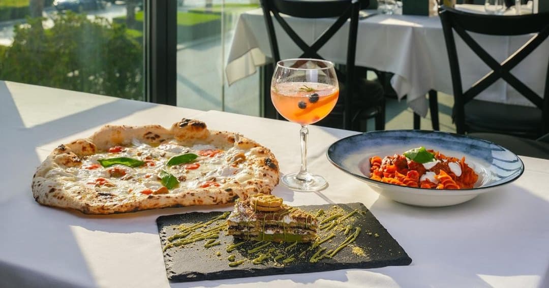 Pizza, Pasta, Dessert and Cocktail on a restaurant table