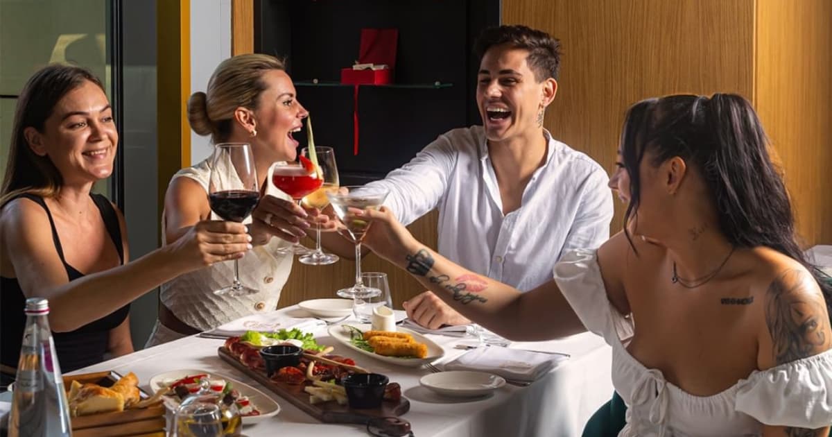 A group of four people sitting at a table toasting their drinks