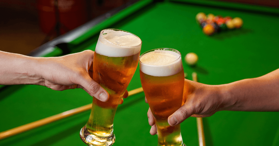 Two beers held over a billiards table