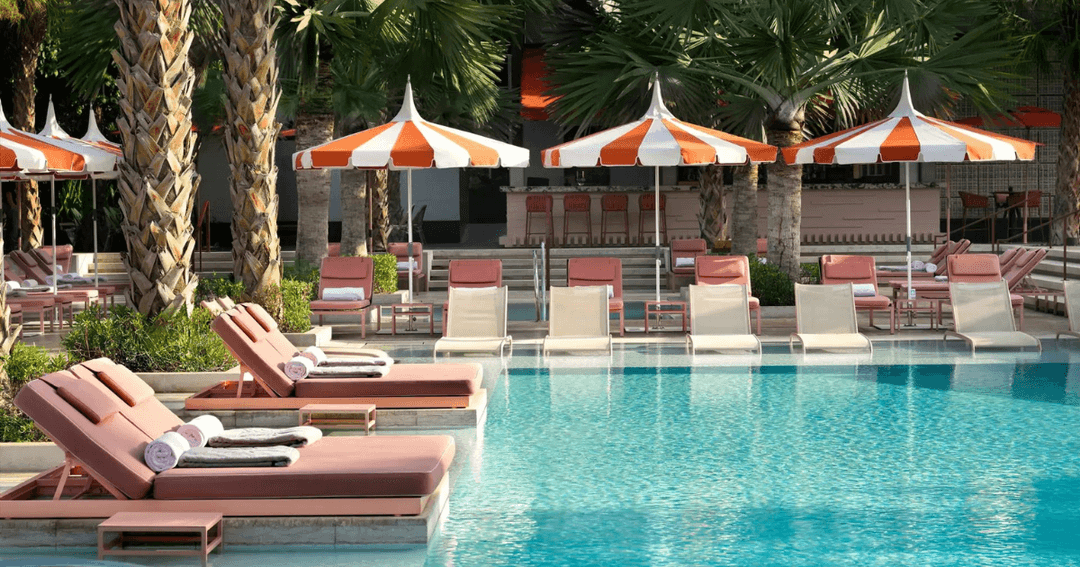 A close-up of the sun loungers and umbrellas by the pool at Alizée on Bluewaters Island, showcasing the relaxing ambiance with pink cushioned loungers and striped orange and white umbrellas.