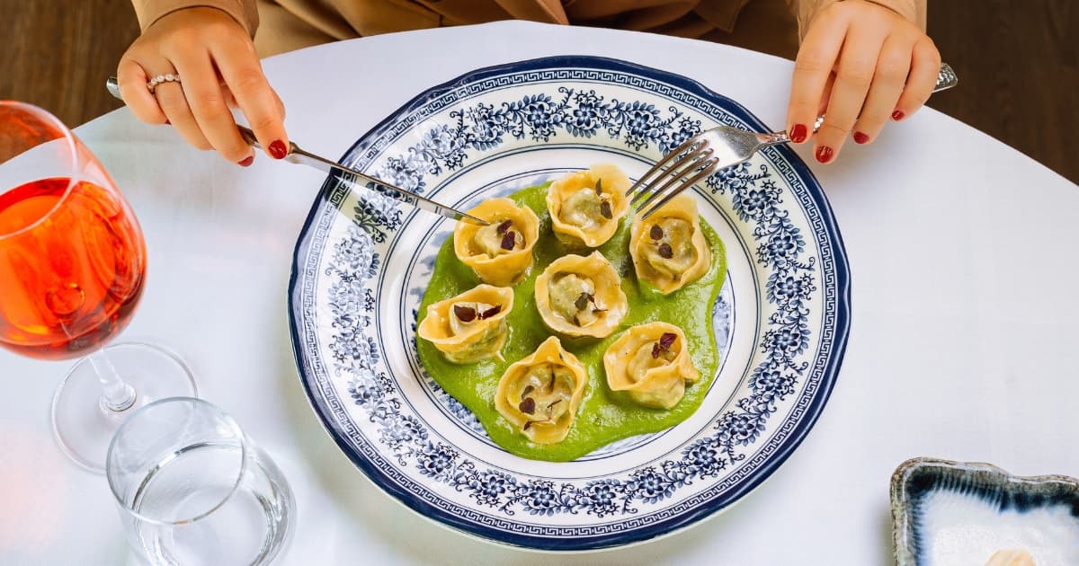 Lady sitting at table eating a pasta dish